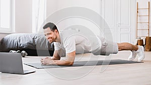 Man Exercising At Laptop Doing Plank During Online Workout Indoors