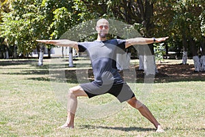 Man exercising in park. Smiling caucasian male doing core workout on grass