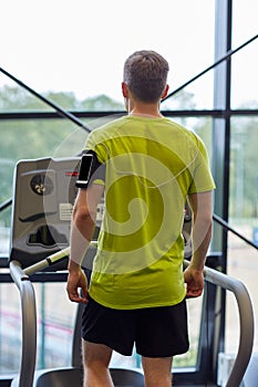 Man exercising on treadmill in gym from back