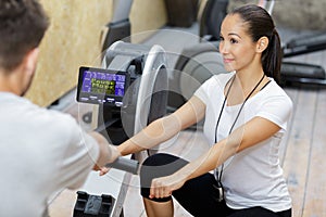 Man exercising using rowing machine coached by trainer