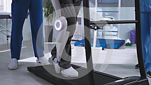 Man in exoskeleton walking on treadmill near rehabilitation therapists