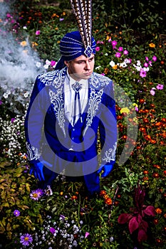 Man in expensive dark blue suit of illusionist pose on flower meadow.