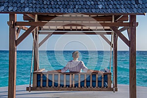 Man in expensive shirt relaxing at the swing  at the tropical island luxury resort