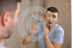 Man experimenting pain while brushing his teeth