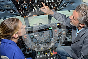 Man explaining controls aircraft cockpit to young lady