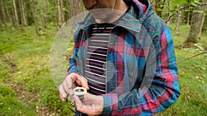 Man explorer searching direction with compass in summer forest