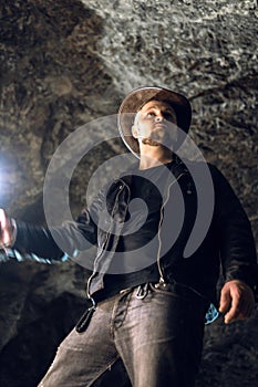 Man exploring huge cave. Adventure travellers dressed cowboy hat and backpack, leather jacket. extreme, tourist route. ancient