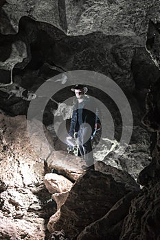 Man exploring huge cave. Adventure travellers dressed cowboy hat and leather jacket. extreme, tourist route. ancient crystal