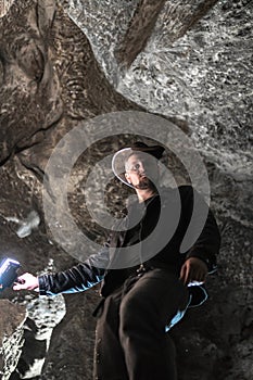 Man exploring huge cave. Adventure travellers dressed cowboy hat and leather jacket. extreme, tourist route. ancient crystal