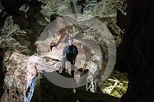 Man exploring huge cave. Adventure travellers dressed cowboy hat and leather jacket. extreme vacation, tourist route. ancient