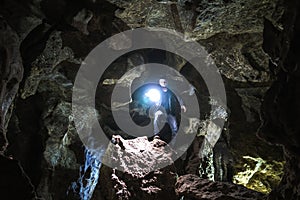 Man exploring huge cave. Adventure travellers dressed cowboy hat and leather jacket. extreme vacation, tourist route. ancient