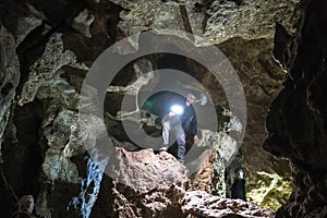 Man exploring huge cave. Adventure travellers dressed cowboy hat and leather jacket. extreme vacation, tourist route. ancient