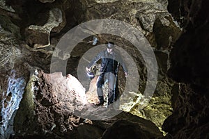 Man exploring huge cave. Adventure travellers dressed cowboy hat and leather jacket. extreme vacation, tourist route. ancient