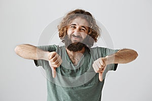 Man expressed dislike with body language. Studio shot of handsome arabian with beard and curly hair frowning and showing