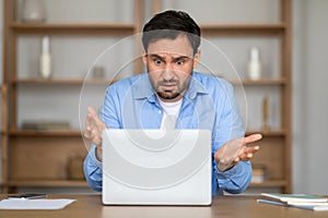 Man Expressing Confusion While Working on Laptop in Home Office