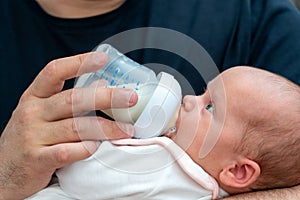 Man expressing his deep love as a father, holding newborn and feeding formula milk