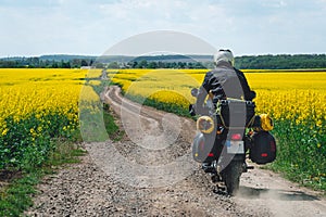 Man extreme sport riding touring enduro motorcycle on dirt. beautiful yellow field of flowers. World adventure rider. Tourist bike