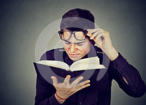 Man with eye glasses trying to read book has sight problems