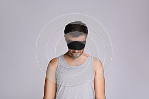 Man with eye mask in sleepwalking state on grey background