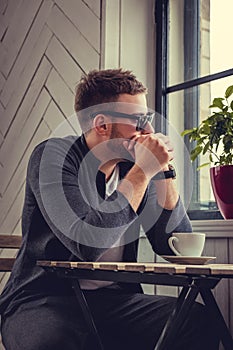 A man in eyeglasses drinking morning coffee.