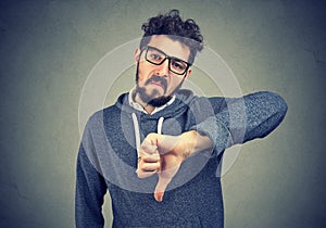 Man in eyeglasses showing dislike with thumb down gesture