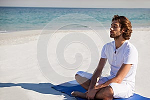 Man with eyes closed meditating at beach