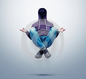 Man without a face in a hoodie levitates in the air in the lotus position, on a dark background.