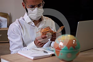 Man with face mask holding a stack of cash, financial adviser working