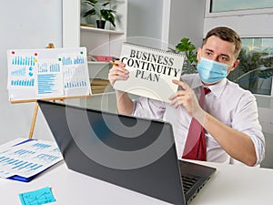 Man in face mask shows Business continuity plan while online meeting.