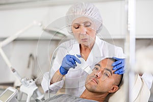Man on facial skin rejuvenation procedures using various hardware procedures in clinic