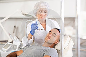 Man on facial skin rejuvenation procedures using various hardware procedures in clinic