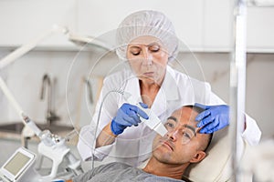 Man on facial skin rejuvenation procedures using various hardware procedures in clinic