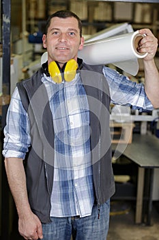 man in factory holding roll film on shoulder
