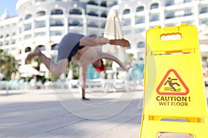 Man falling near yellow plastic sign caution wet floor closeup