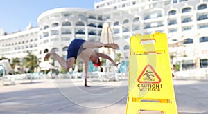 Man falling near yellow plastic sign caution wet floor closeup