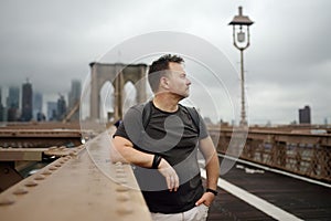 Man on a famous brooklyn bridge in rainy summer day