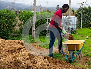 Man farmer with barrow during working with fertilizers