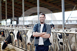 Man or farmer with cows in cowshed on dairy farm