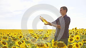 Man farmer hand hold bottle of lifestyle sunflower oil the field at sunset. Sunflower oil improves skin health and