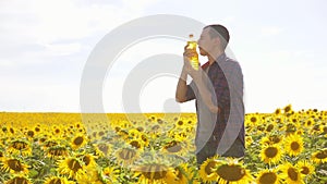 Man farmer hand hold bottle of sunflower oil n the field lifestyle at sunset. Sunflower oil improves skin health and