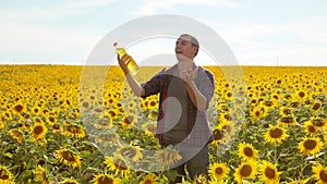 Man farmer hand hold bottle of sunflower oil n the field at sunset. Sunflower oil improves skin health and promote