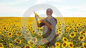 Man farmer hand hold bottle of sunflower oil n the field at sunset. Sunflower oil improves skin health and promote cell