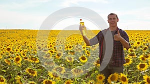 Man farmer hand hold bottle of sunflower oil n the field at sunset. Sunflower oil improves skin health and promote cell