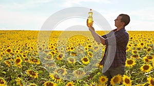 Man farmer hand hold bottle of sunflower oil n the field at sunset. Sunflower oil improves skin health and promote cell