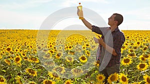 Man farmer hand hold bottle of sunflower oil n the field at sunset. Sunflower oil improves skin health and promote cell