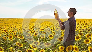 Man farmer hand hold bottle of sunflower oil n the field at sunset. Sunflower oil improves skin health and promote cell