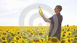 Man farmer hand hold bottle of sunflower oil n the field at sunset. Sunflower oil improves skin lifestyle health and