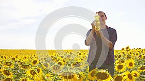 Man farmer hand hold bottle of sunflower oil n the field at sunset. Sunflower oil lifestyle improves skin health and