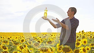 Man farmer hand hold lifestyle bottle of sunflower oil the field at sunset. Sunflower oil improves skin health and
