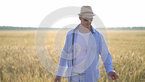 Man farmer in a hat walking in wheat field